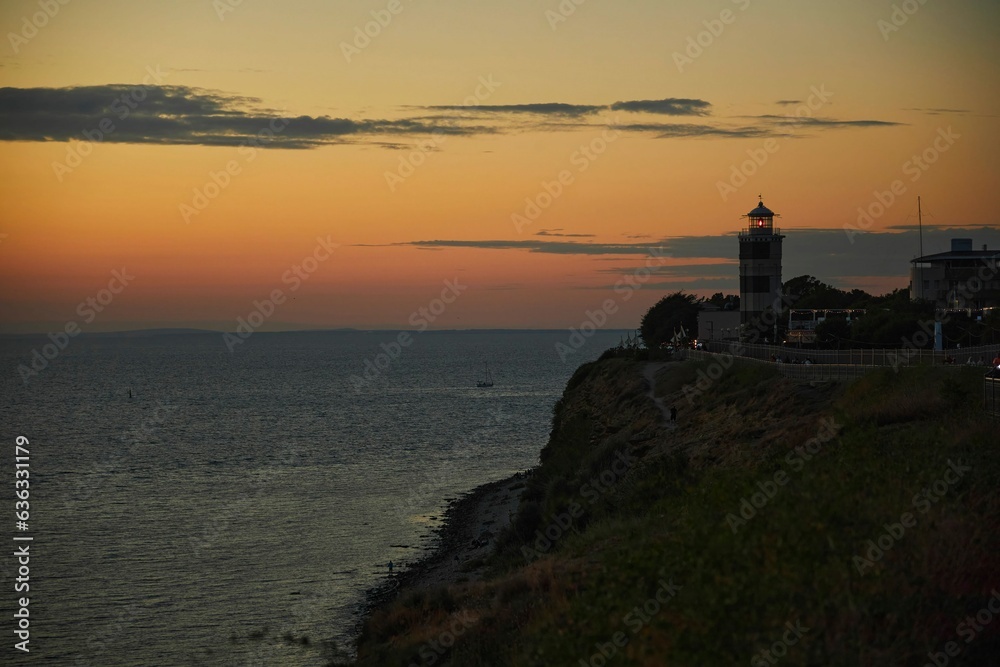 A beautiful landscape with a sunset in the sea and a lighthouse.