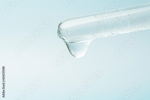 Pipette dropping liquid into glass tubes. Laboratory glassware with dropper into test tube close up macro. laboratory equipment glassware. Concept of medical or science laboratory. blue background.