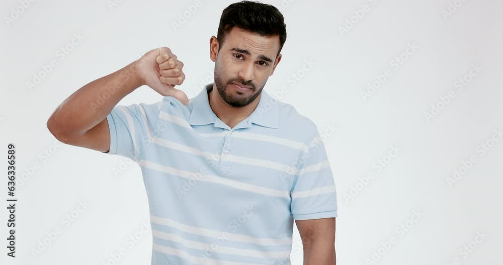 Thumbs down, face and hands of man in studio for rejection of bad news, emoji sign and no feedback on white background. Portrait of sad indian model show negative review, wrong decision and failure Thumbs down, face and hands of man in studio for rejection of bad news, emoji sign and no feedback on white background. Portrait of sad indian model show negative review, wrong decision and failure