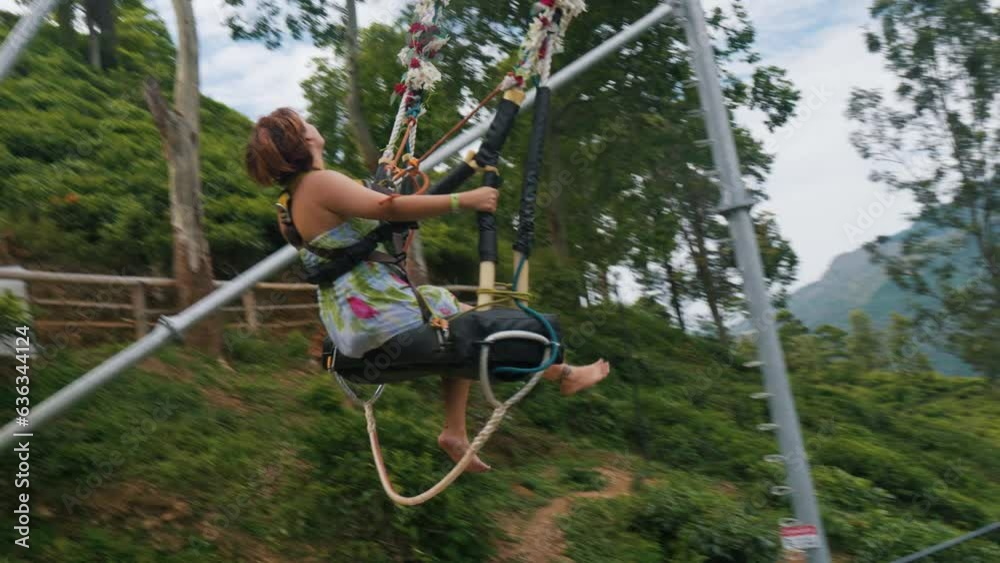 Girl swinging on giant swing against picturesque landscapes of Nuwara Eliya.
