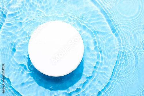 Water blue surface abstract background. Waves and ripples texture of cosmetic aqua moisturizer with bubbles and white product pedestal.