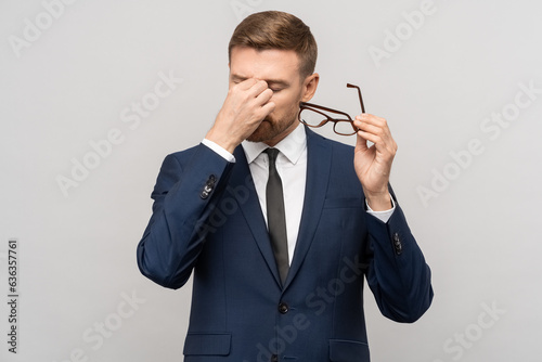 Foto Tired businessman takes off glasses, massaging eyelids of eyes
