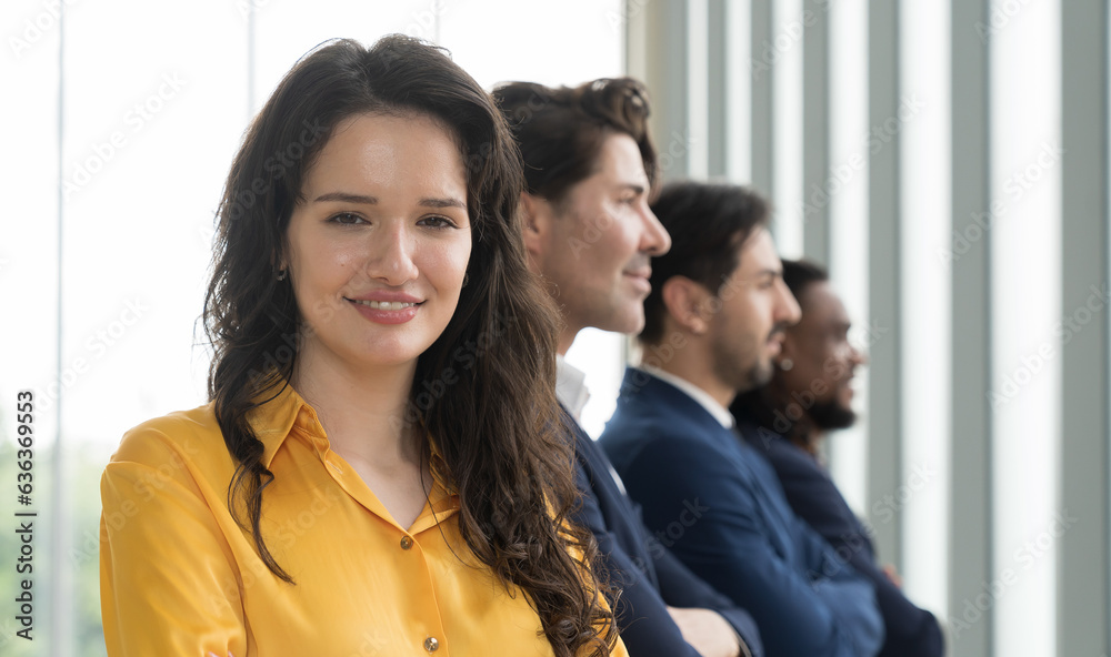 Business woman standing with cross arms with corporate colleagues in modern office. Group of partnership meeting and working together in office Business woman standing with cross arms with corporate colleagues in modern office. Group of partnership meeting and working together in office