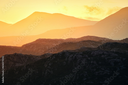 Silhouettes of mountains illuminated by the rising sun. North West Sutherland, Scotland