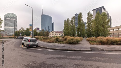 Panorama showing skyscrapers and towers from park with outumn treea and green lawn timelapse. Located between Piazza Gae Aulenti and the Isola district. Traffic on a road. Milan. Italy photo