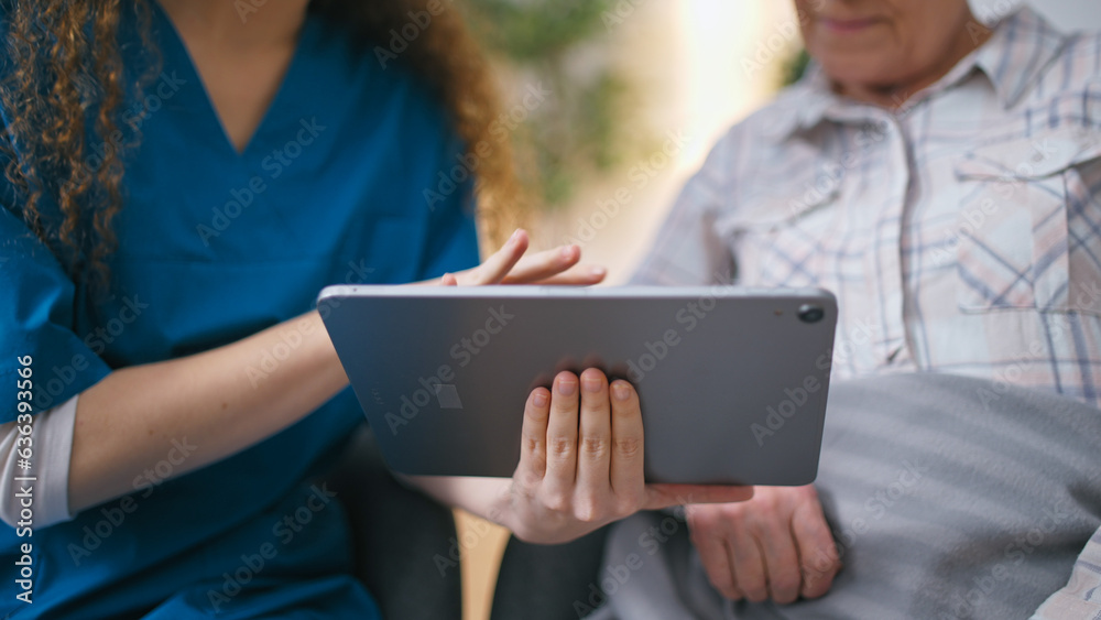 A female volunteer is teaching a senior woman how to use a tablet, introducing her to modern technology A female volunteer is teaching a senior woman how to use a tablet, introducing her to modern technology