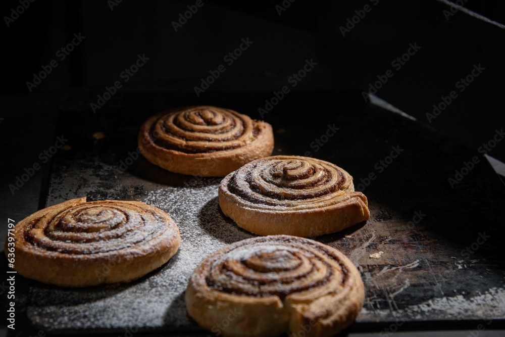 Freshly-baked batch of delicious cinnamon rolls sits on a baking sheet with flour