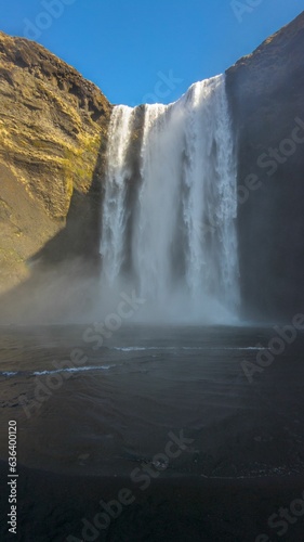 Stunning landscape of a majestic waterfall surrounded by an expanse of dry  golden grass