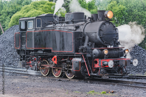 Retro steam locomotive stands near depot.