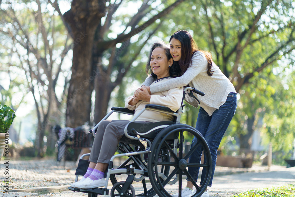Asian senior woman in wheelchair with happy daughter. Family relationship retired woman sitting on wheelchair in the park age care at retirement home. Asian senior woman in wheelchair with happy daughter. Family relationship retired woman sitting on wheelchair in the park age care at retirement home.