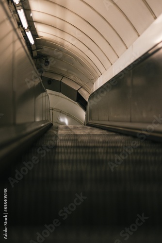 Escalator in a train station, with its glass walls reflecting the bright lights of the station photo
