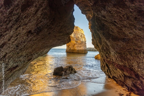 Scenic view of rocky formations on the coastline against the sea at golden hour