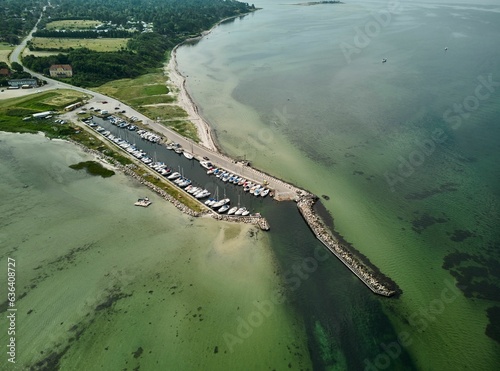 Aerial shot of the Kulhuse harbor, with docked boats, the breakwater extended in the water, Denmark