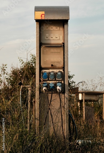 old style gas pump in the middle of nowhere surrounded by tall grasses