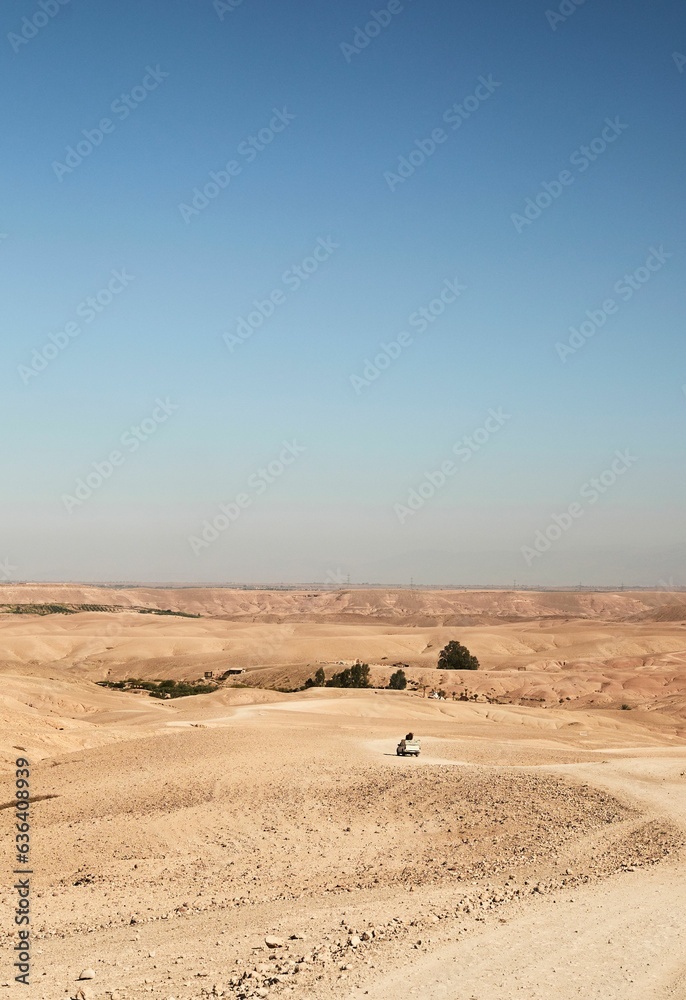 The vehicle driving down the dirt road by the trees The vehicle driving down the dirt road by the trees