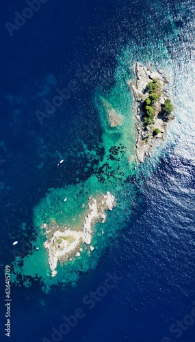Aerial view of a rocky island with several boats floating in the vicinity in Petrovac, Montenegro