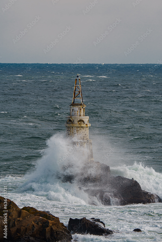 Beautiful shot of a water hitting an old lighthouse in the sea and making big powerful splash