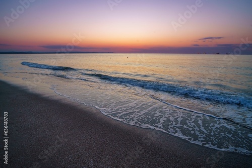 Aerial view of sea waves breaking beach during sunset