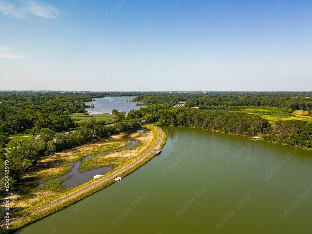 Fototapeta premium Aerial top down view over a park with a green pond on a sunny day on Long Island, NY