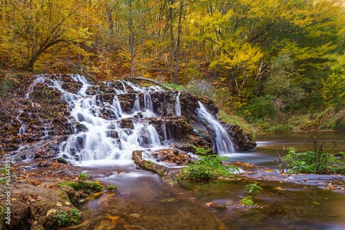 Fototapeta Naklejka Na Ścianę i Meble -  Low-angle of Dokuzak waterfall in autumn, yellowing trees background