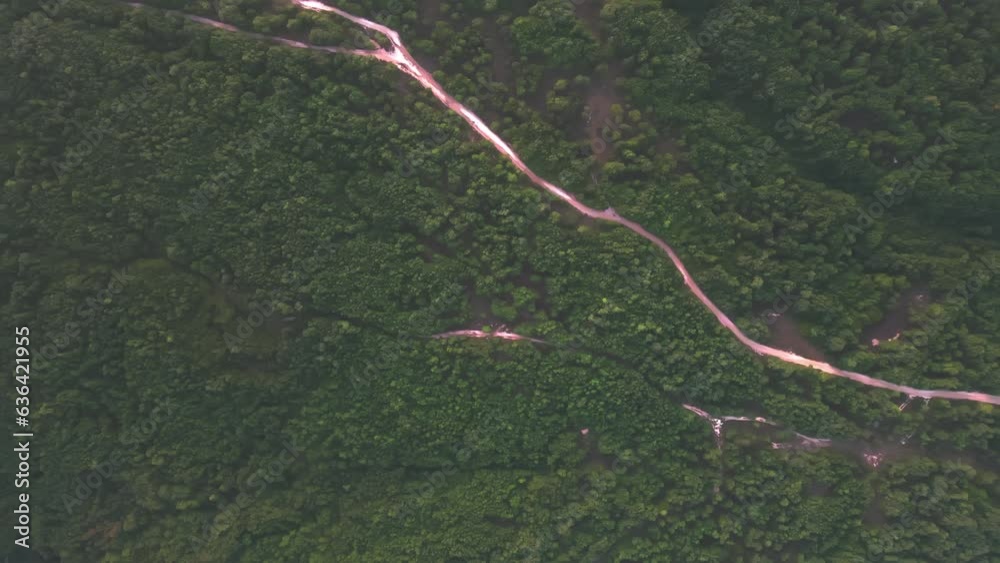 Drone shot over a road in mountains with green lush forest Drone shot over a road in mountains with green lush forest