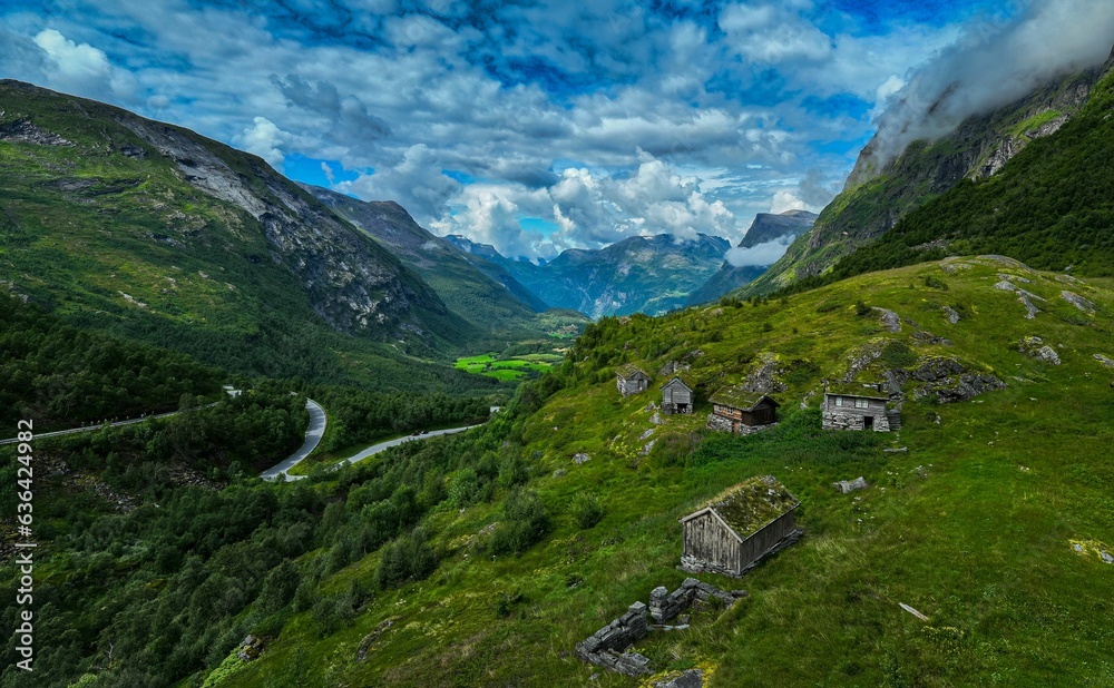 Scenic landscape featuring a mountain range with lush green grass and small cottages