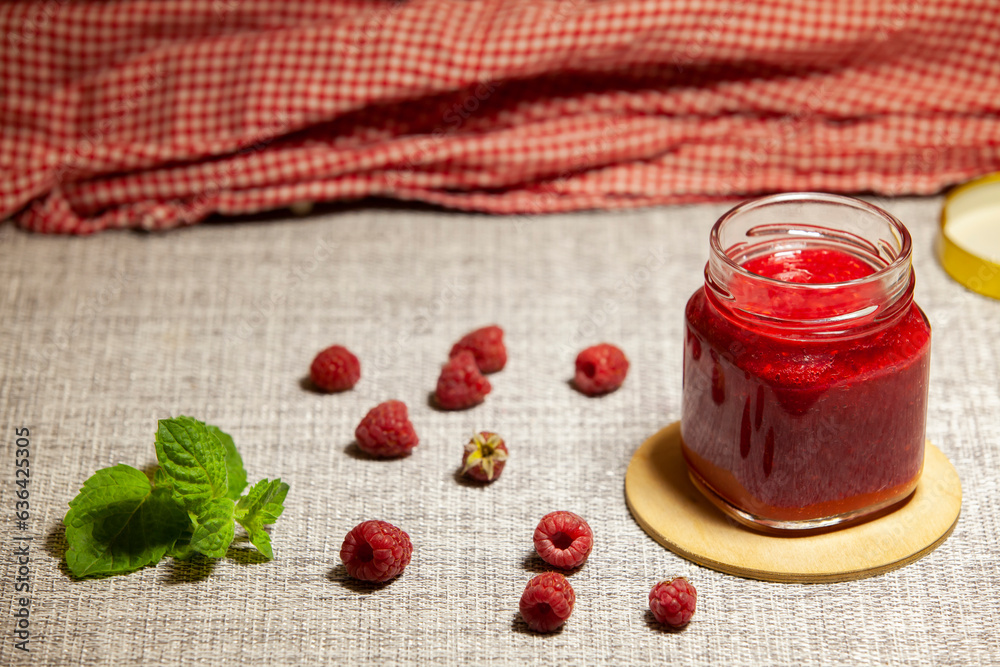 Homemade raspberry jam in a glass jar. Food preservation. Healthy desserts concept.