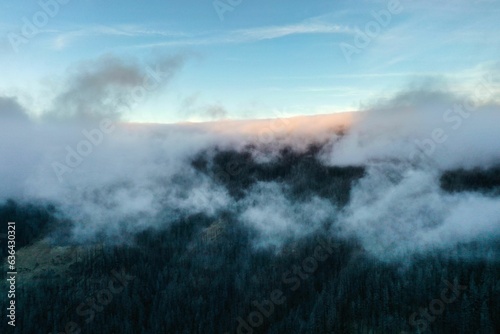 mountains with trees all around and clouds in the sky, viewed from atop a hill