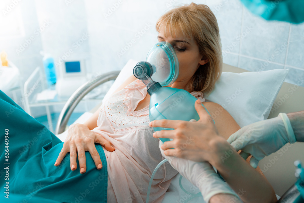 Pregnant woman lying in bed while inhaling nitrous oxide before giving