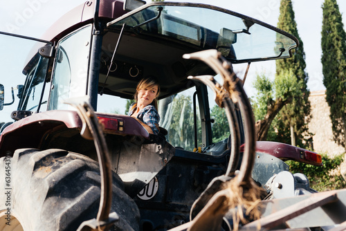 Female farmer reversing tractor during summer day