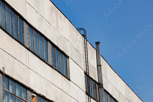 Exterior wall of an old industrial building against blue sky. Industrial site city area. Abandoned industry concept.