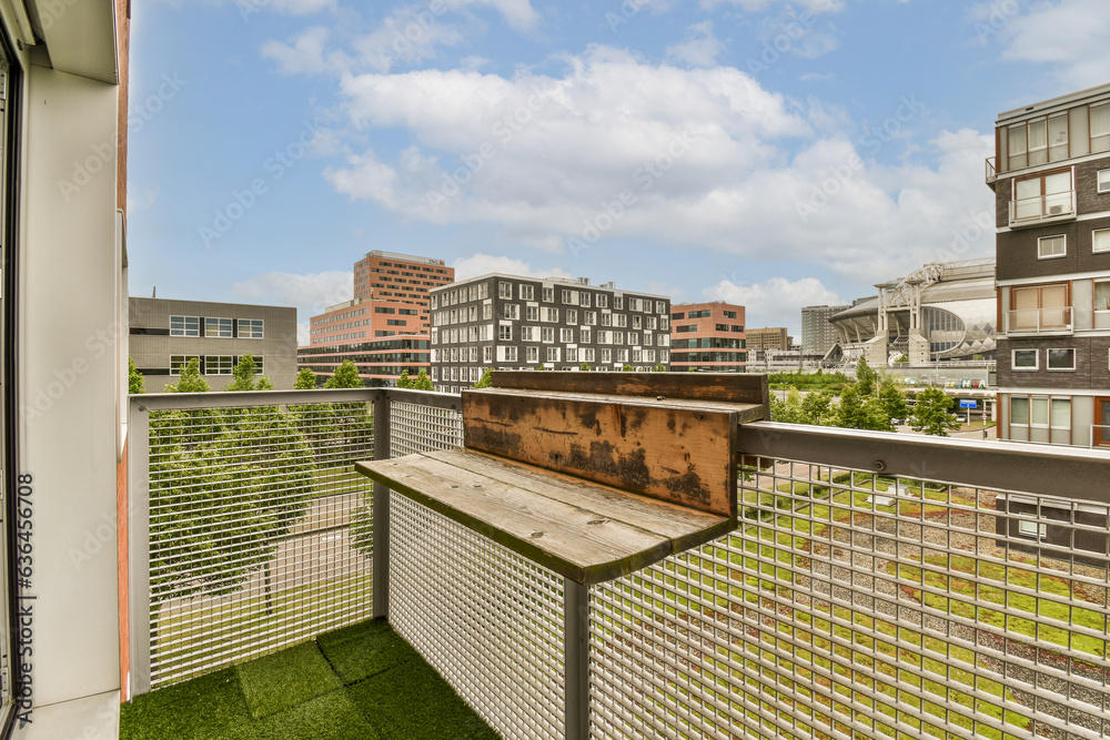 a balcony with grass and buildings in the background, taken from an apartment building's roof top deck area