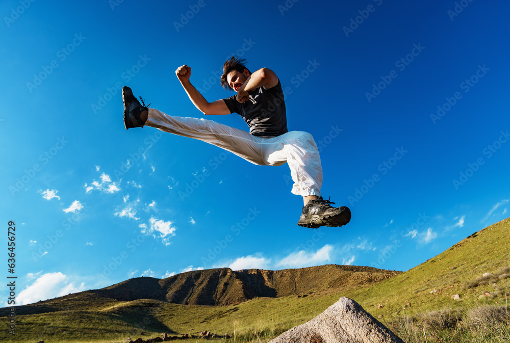 Handsome athletic young man jumping on mountains background Handsome athletic young man jumping on mountains background