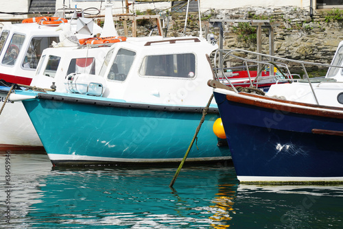 Colourful fishing boats moored at harbour of historical fishing village in Cornwall