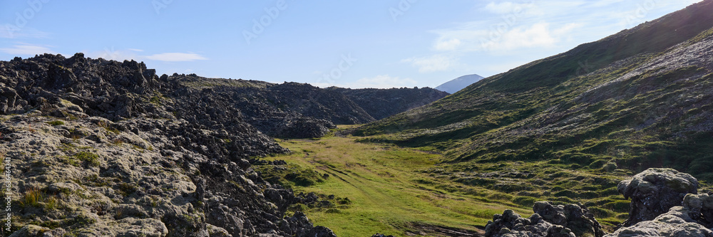 In the foreground a lava field covered with moss, in the background mountains.Helgafellssveit, Iceland.