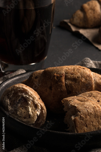 Traditional colombian food, Croissants and Handmade Corn and Flour Breads on a black plate served on a dark table, accompanied by hot black coffee.