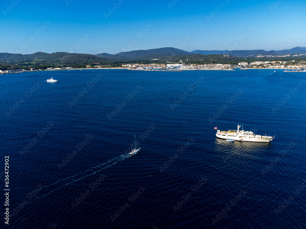 Aerial view on blue water of Gulf of Saint-Tropez, sail boats, houses of Port Grimaud, Port Cogolin, summer vacation in Provence, France