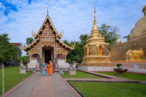 Beautiful women in Thai dress make merit offer food with monks to Asian traditional Buddhism at Wat Phra Singh Woramahawihan Temple tourist attraction and famous place in Chiang Mai, Thailand.