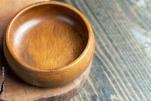 Wooden bowl on wooden table, empty round bowl for groceries and food