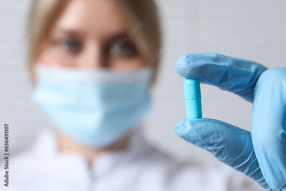 Doctor holding pill on light background, selective focus. Space for text Doctor holding pill on light background, selective focus. Space for text
