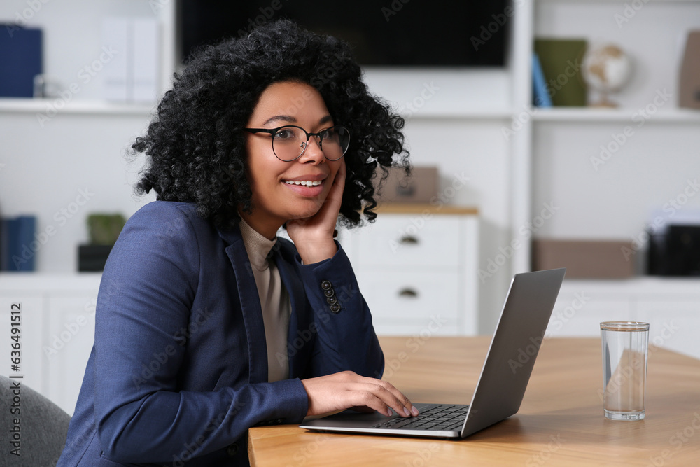 Young woman working on laptop at table in office Young woman working on laptop at table in office
