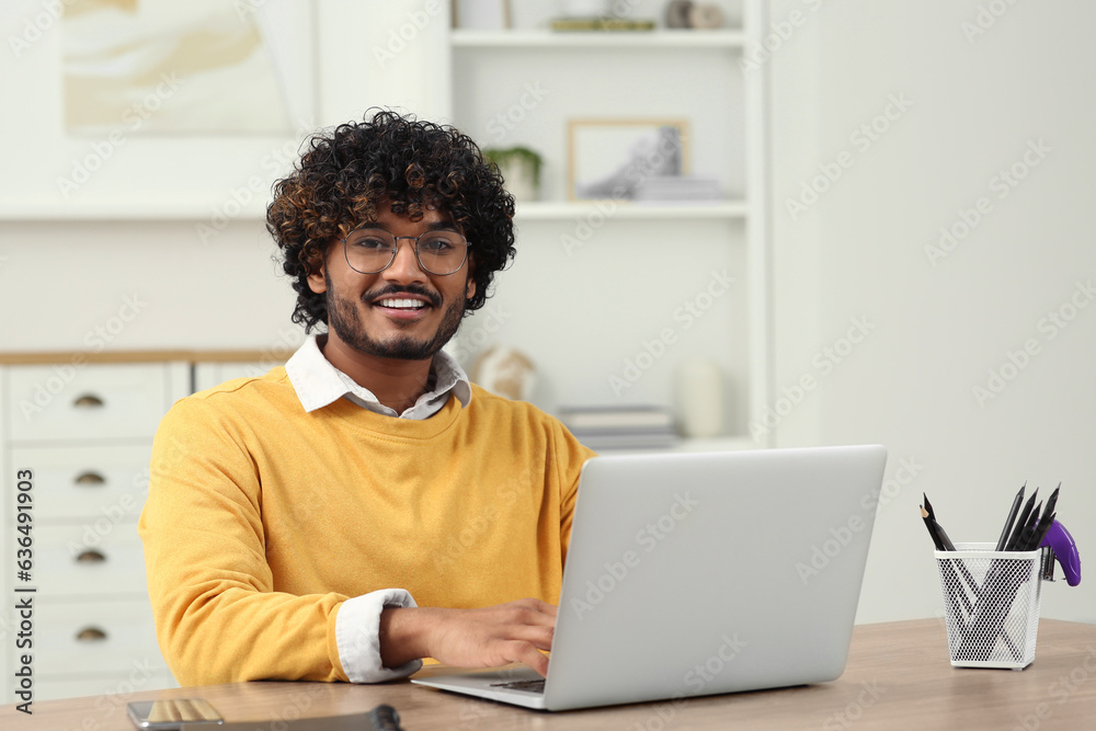 Handsome smiling man using laptop in room Handsome smiling man using laptop in room
