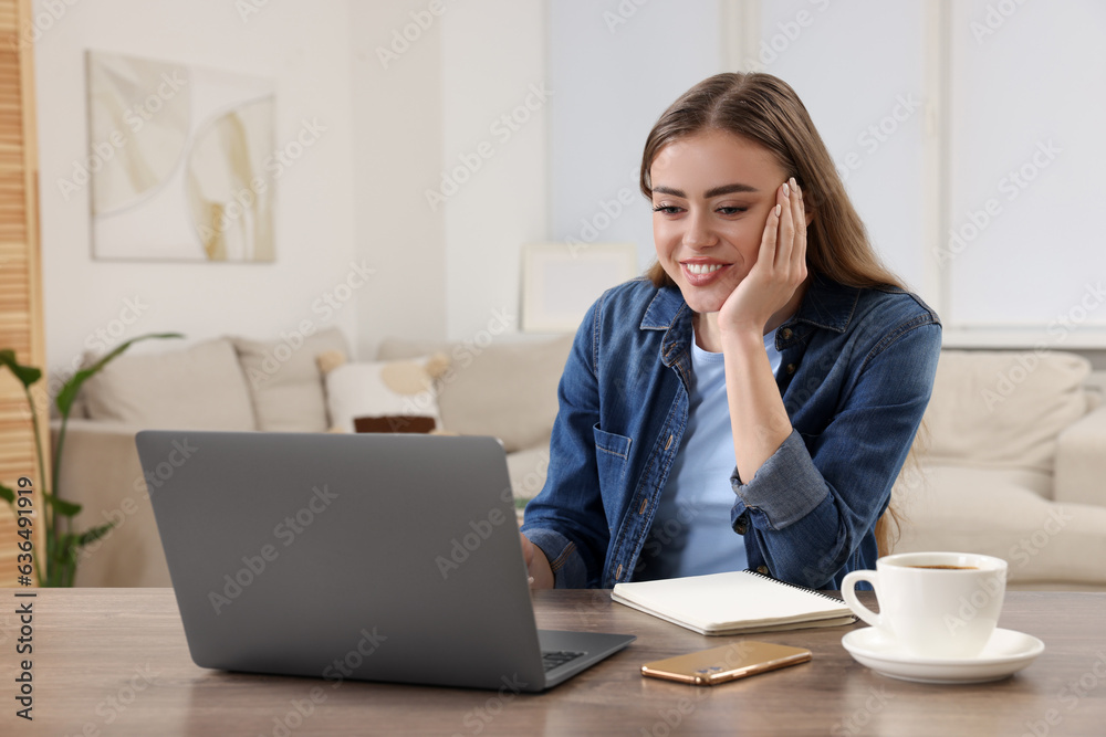 Happy woman with laptop at wooden table in room Happy woman with laptop at wooden table in room