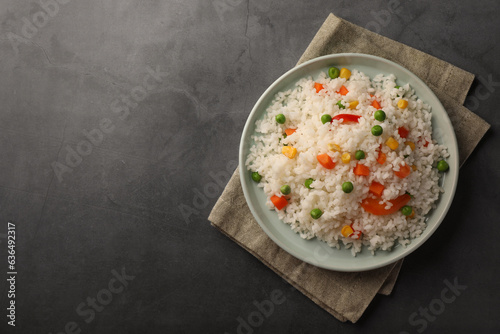 Delicious rice with vegetables on grey table, top view. Space for text