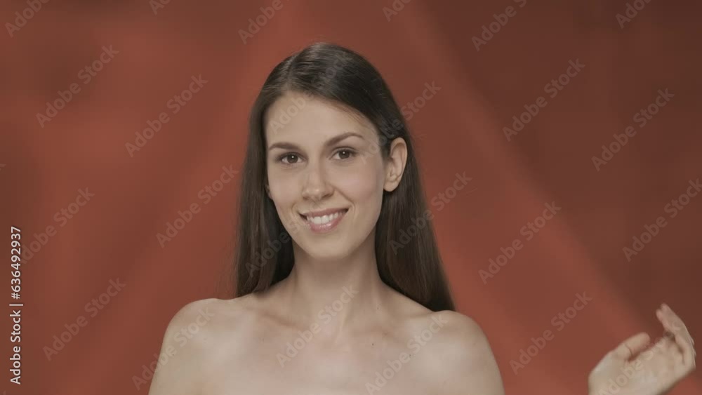 A woman touches the skin under her eyes, demonstrating the absence of wrinkles. Portrait of a woman on a red background close up. The concept of natural beauty, plastic surgery, cosmetology. HDR A woman touches the skin under her eyes, demonstrating the absence of wrinkles. Portrait of a woman on a red background close up. The concept of natural beauty, plastic surgery, cosmetology. HDR