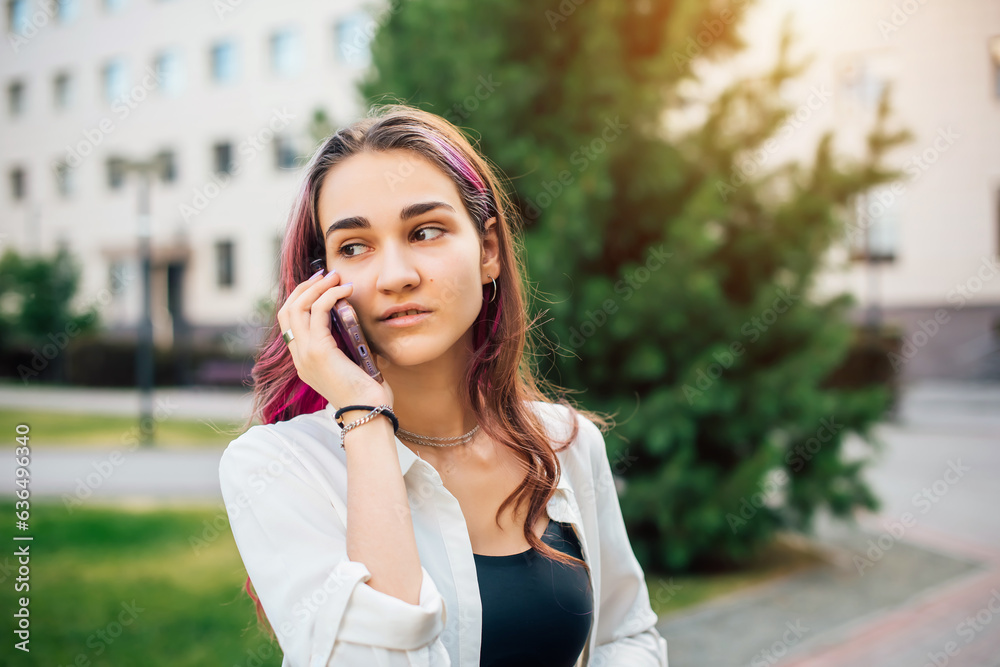Portrait of a beautiful young brunette woman talking on mobile phone outdoors. Lovely female student standing on the street. Portrait of a beautiful young brunette woman talking on mobile phone outdoors. Lovely female student standing on the street.