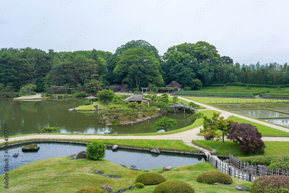 展望台から見下ろすきれいに手入れされた日本庭園の古い茶室と木製太鼓橋のコラボ情景