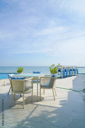 outdoor patio chair and table around swimming pool with sea background