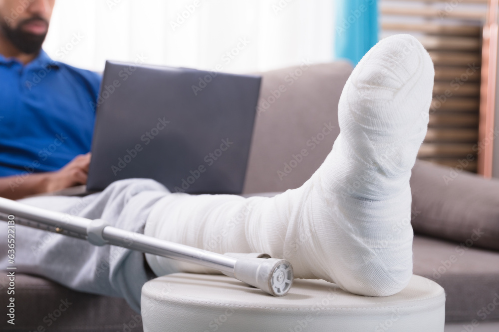 Obraz premium Man With Broken Leg Using Laptop
