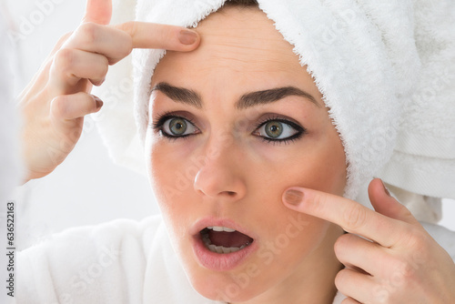 Worried Woman Looking At Pimple On Face